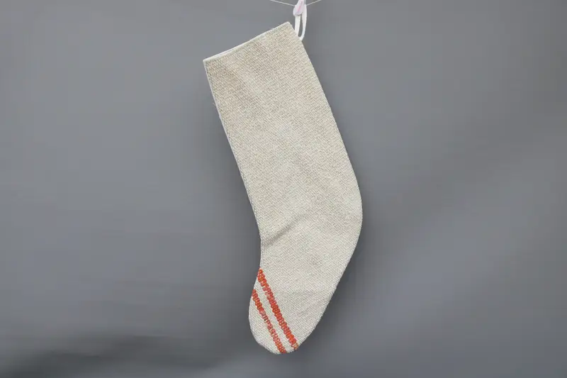 Beigefarbener Weihnachtsstrumpf mit weißen Ornamenten, festliche Weihnachtsdekoration